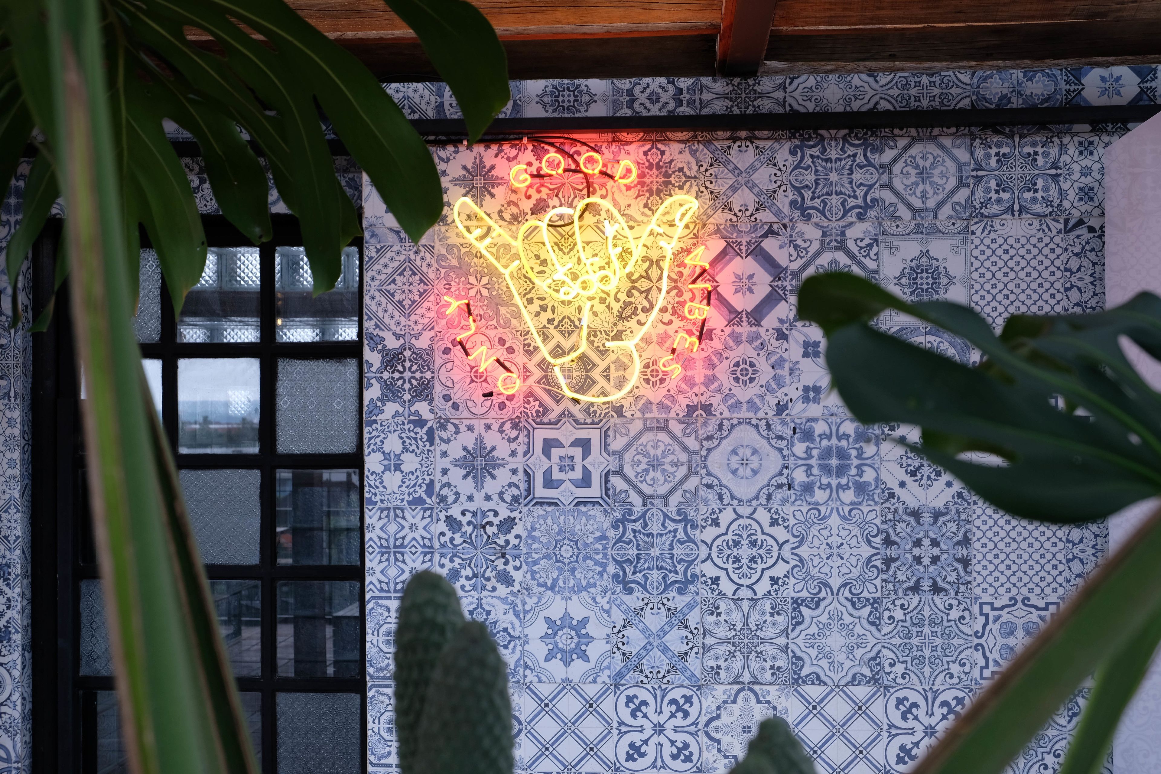 A room with a patterned tile wall, a window with a grid design, and a neon light fixture.