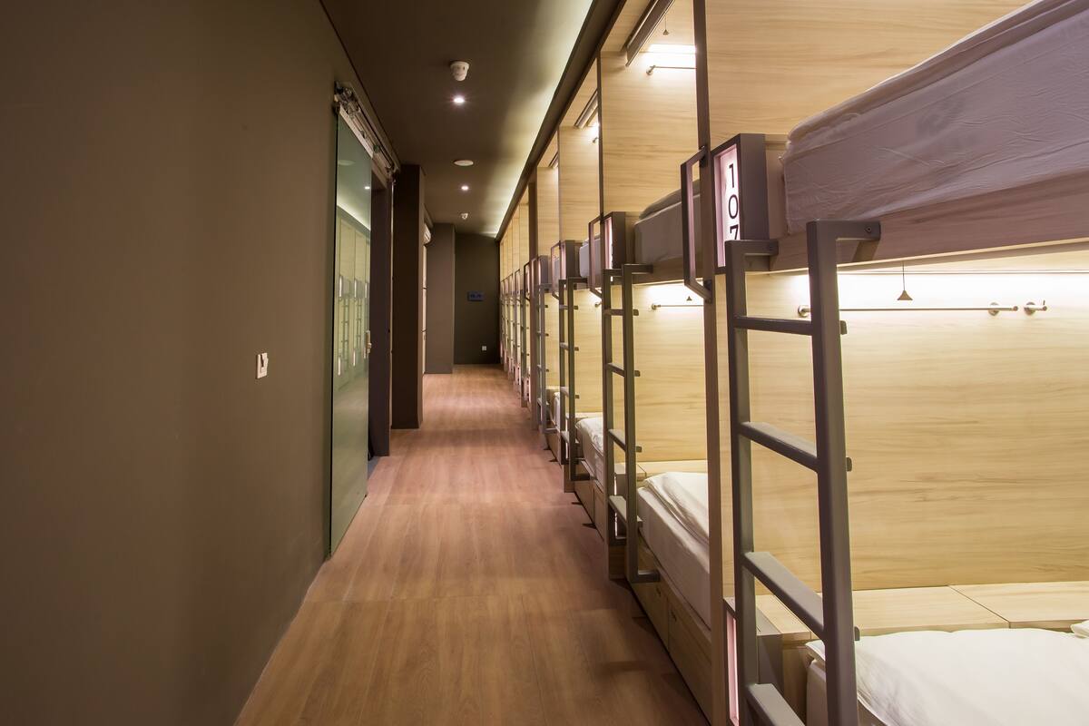 A corridor with bunk beds, wooden flooring, and a sign indicating room number 107.