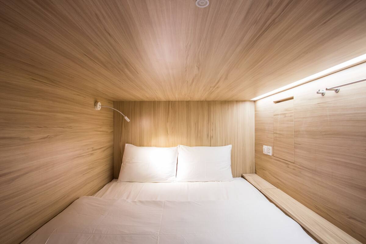 A small, modern bedroom with wooden walls and a single bed.