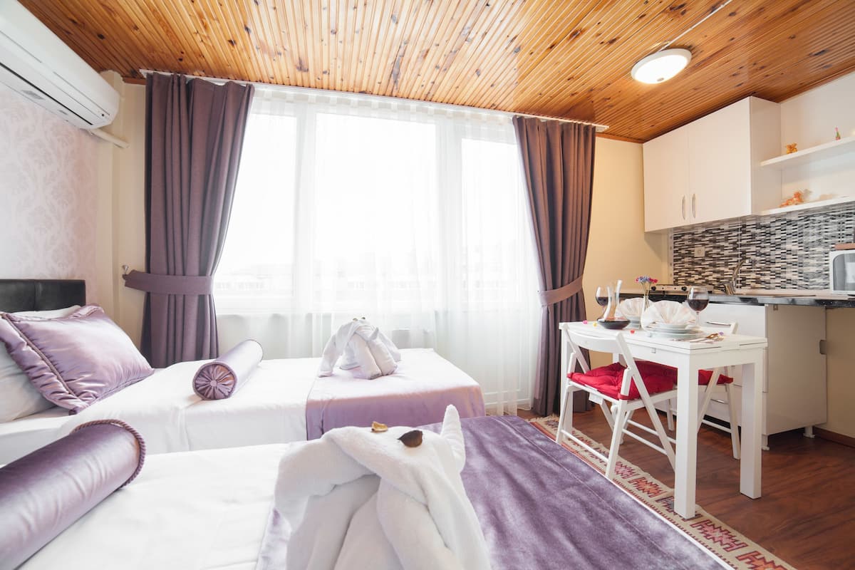 A hotel room with two beds, a dining area, and a kitchenette.