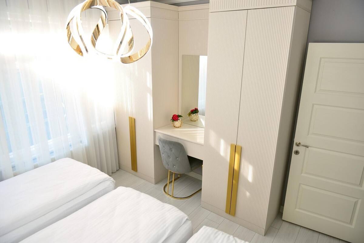 A bedroom with a bed, a vanity with a mirror, and a wardrobe.