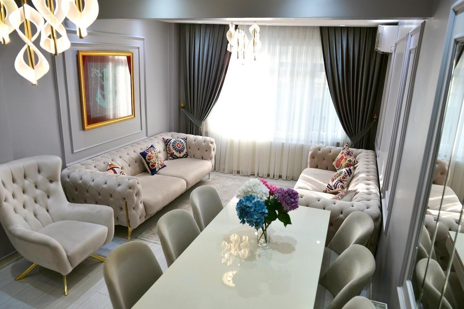 A modern living room with a sofa set, a dining table, and a chandelier.