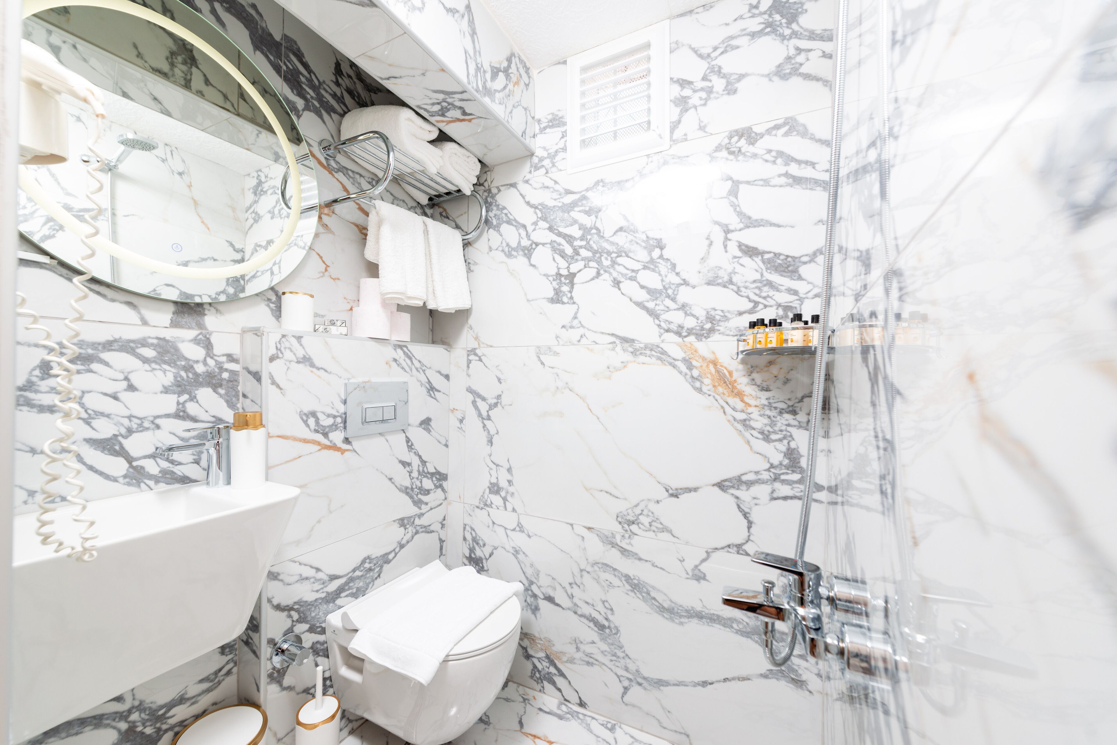 A bathroom with a marble sink, a toilet, a shower, and a mirror.