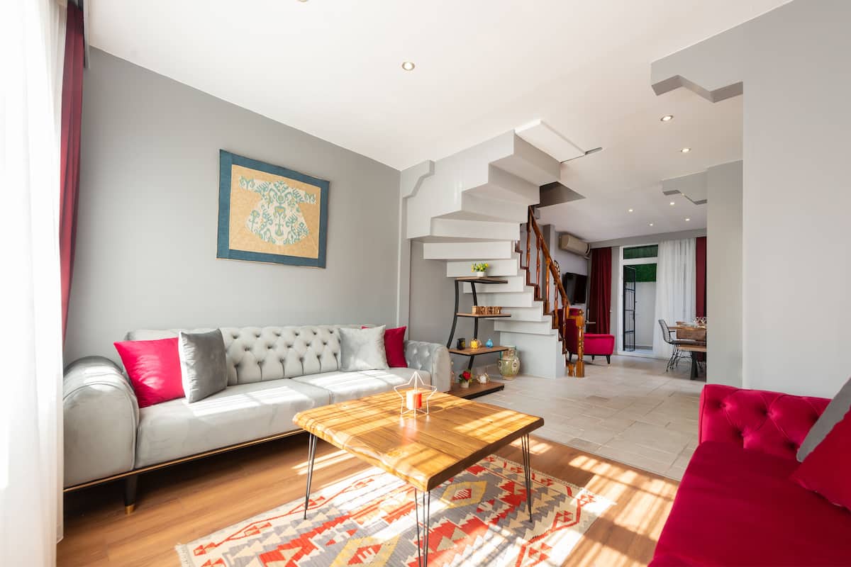 A modern living room with a grey sofa, a wooden coffee table, and a staircase leading to another room.