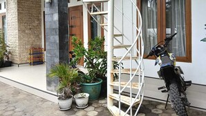 Un edificio con una escalera en espiral, una motocicleta y plantas en macetas.