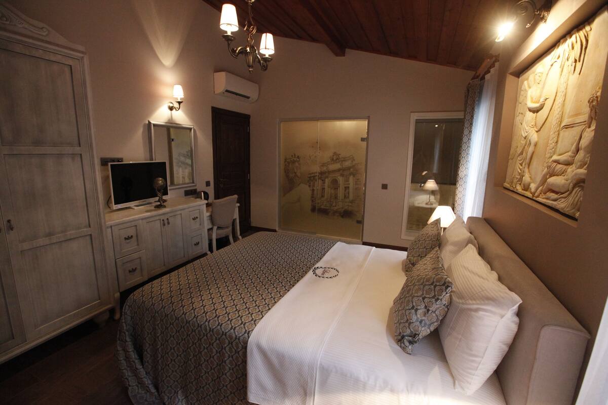 A bedroom with a bed, a desk, a chair, and a large mirror.