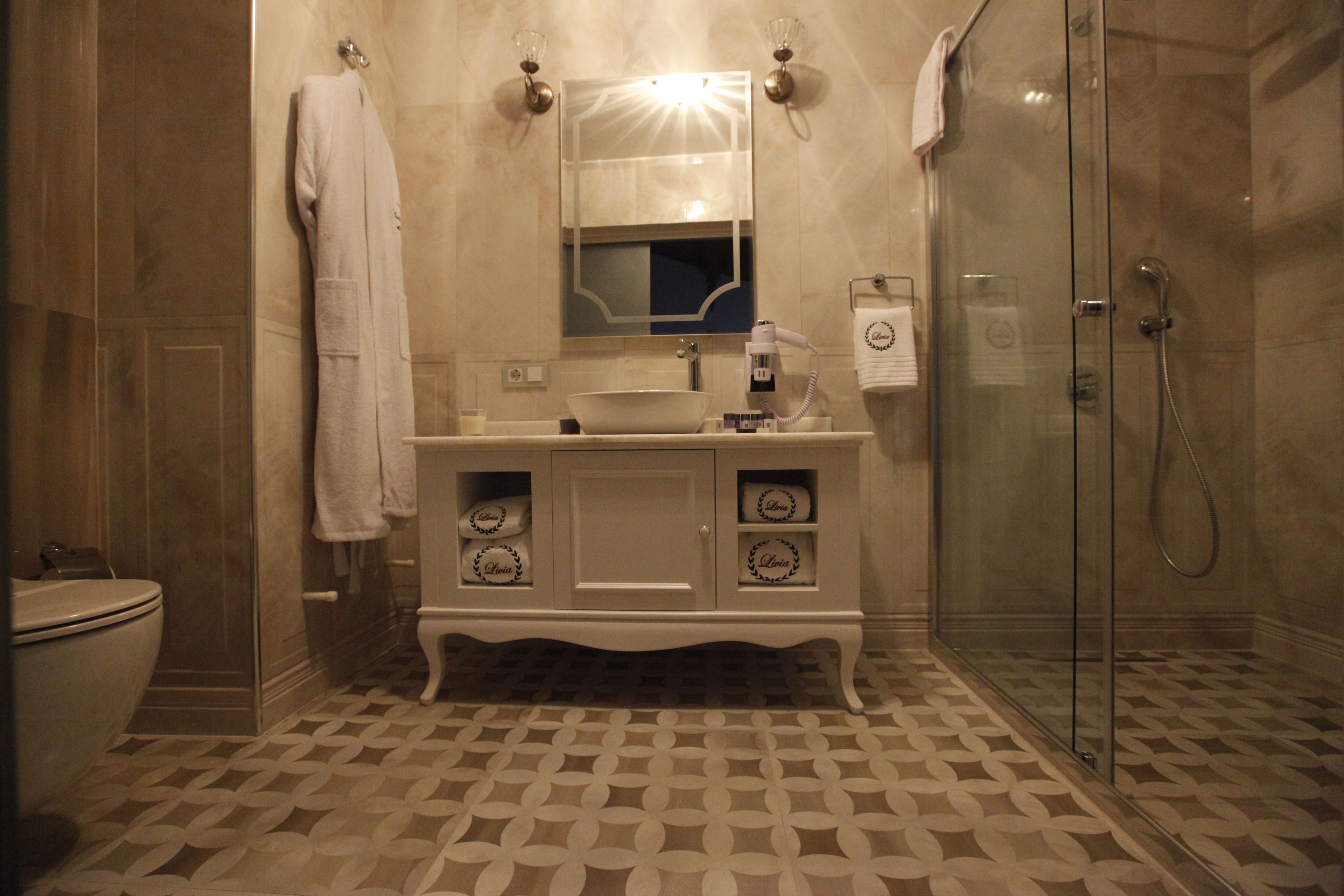 A bathroom with a white vanity, a glass shower enclosure, and patterned floor tiles.