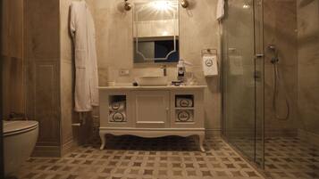 A bathroom with a white vanity, a glass shower enclosure, and patterned floor tiles.