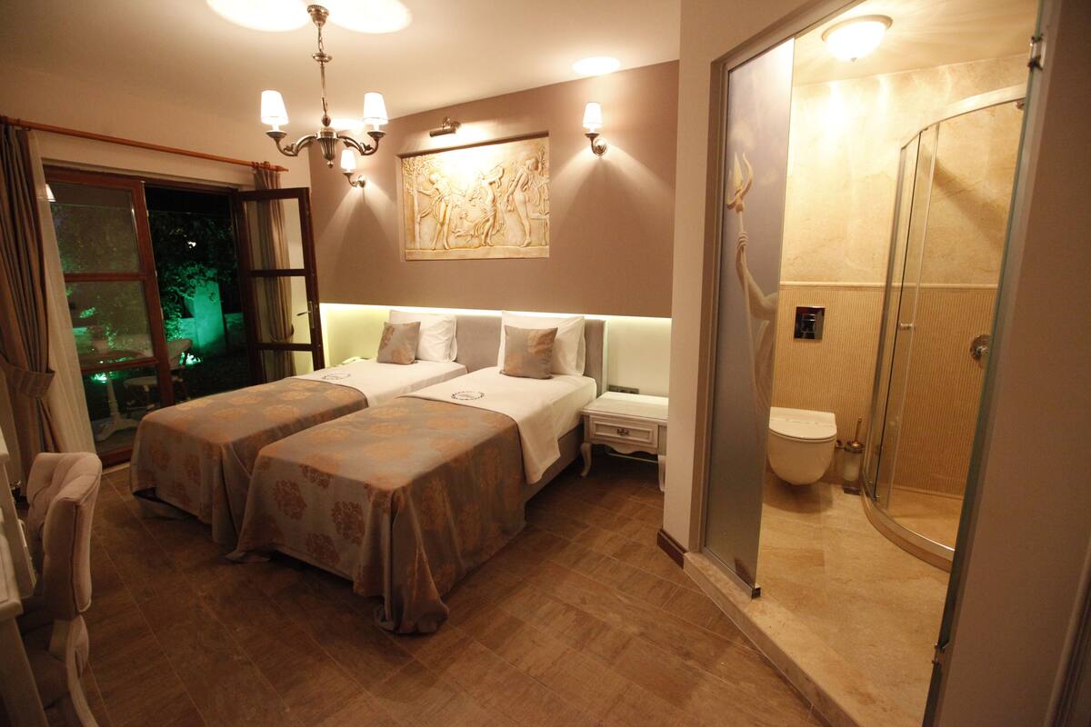 A hotel room with two beds, a shower, and a view of the outdoors.