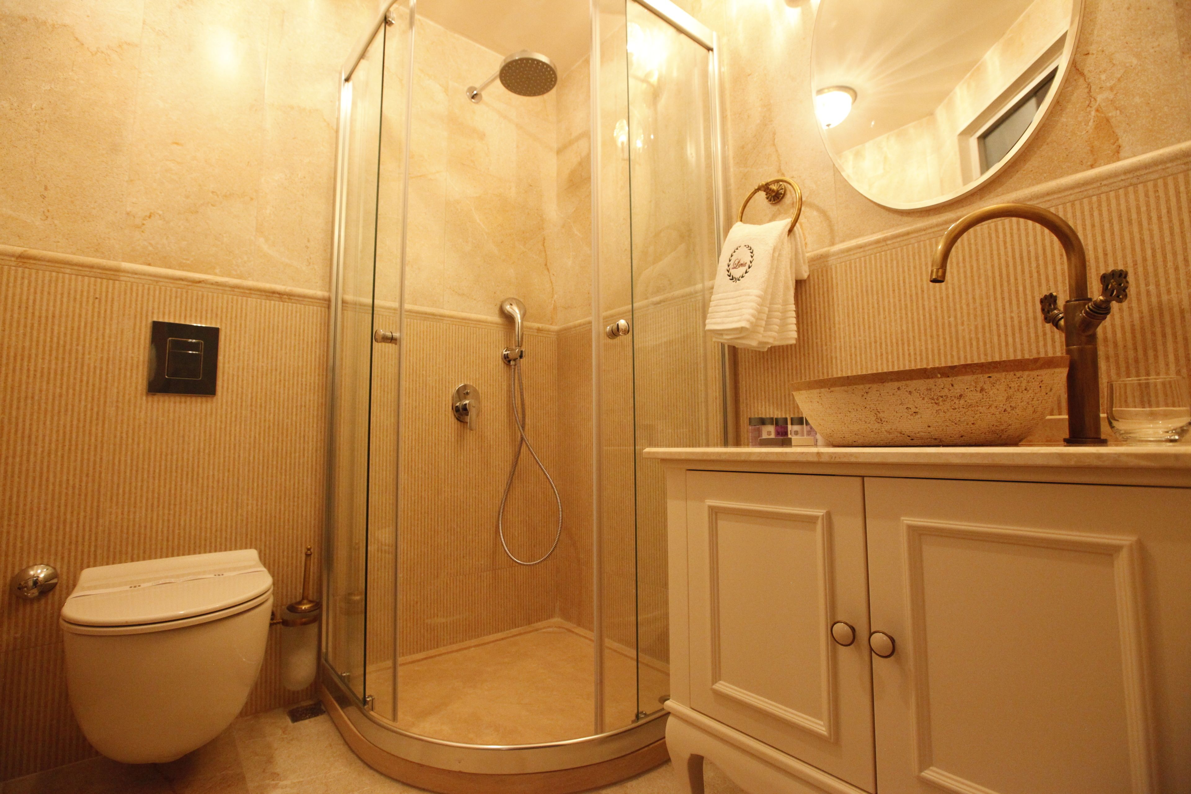 Une salle de bain dotée d’une douche à parois de verre, de toilettes, d’un lavabo avec un receveur décoratif et d’un miroir au-dessus du lavabo.