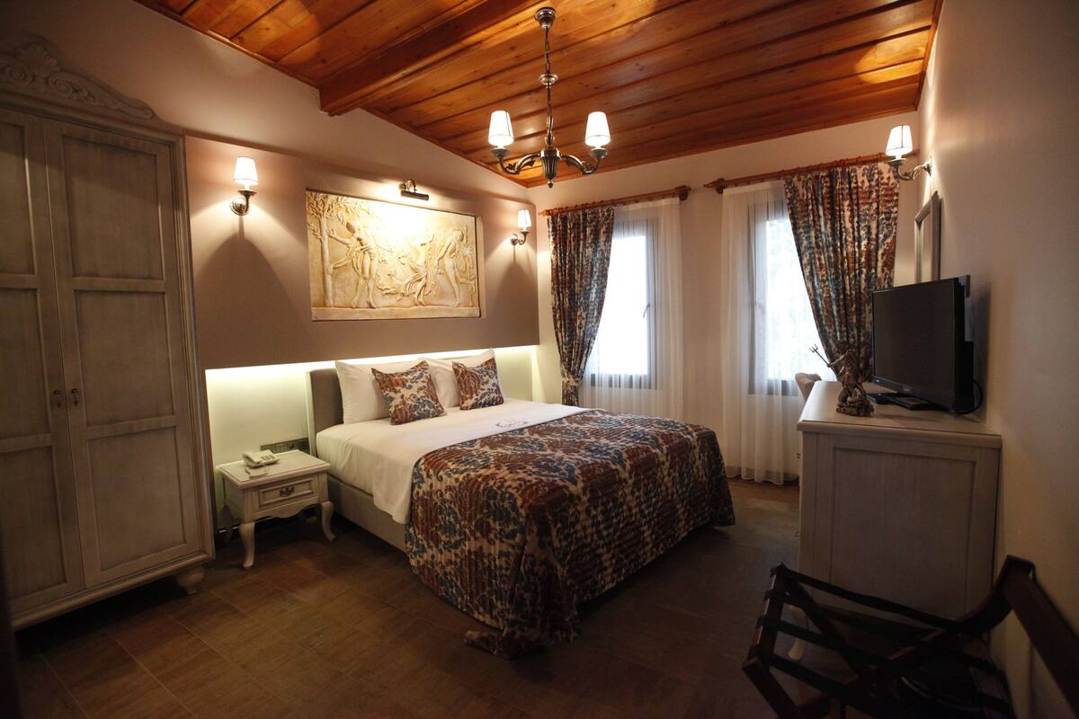 A bedroom with a bed, nightstand, TV, and wardrobe.