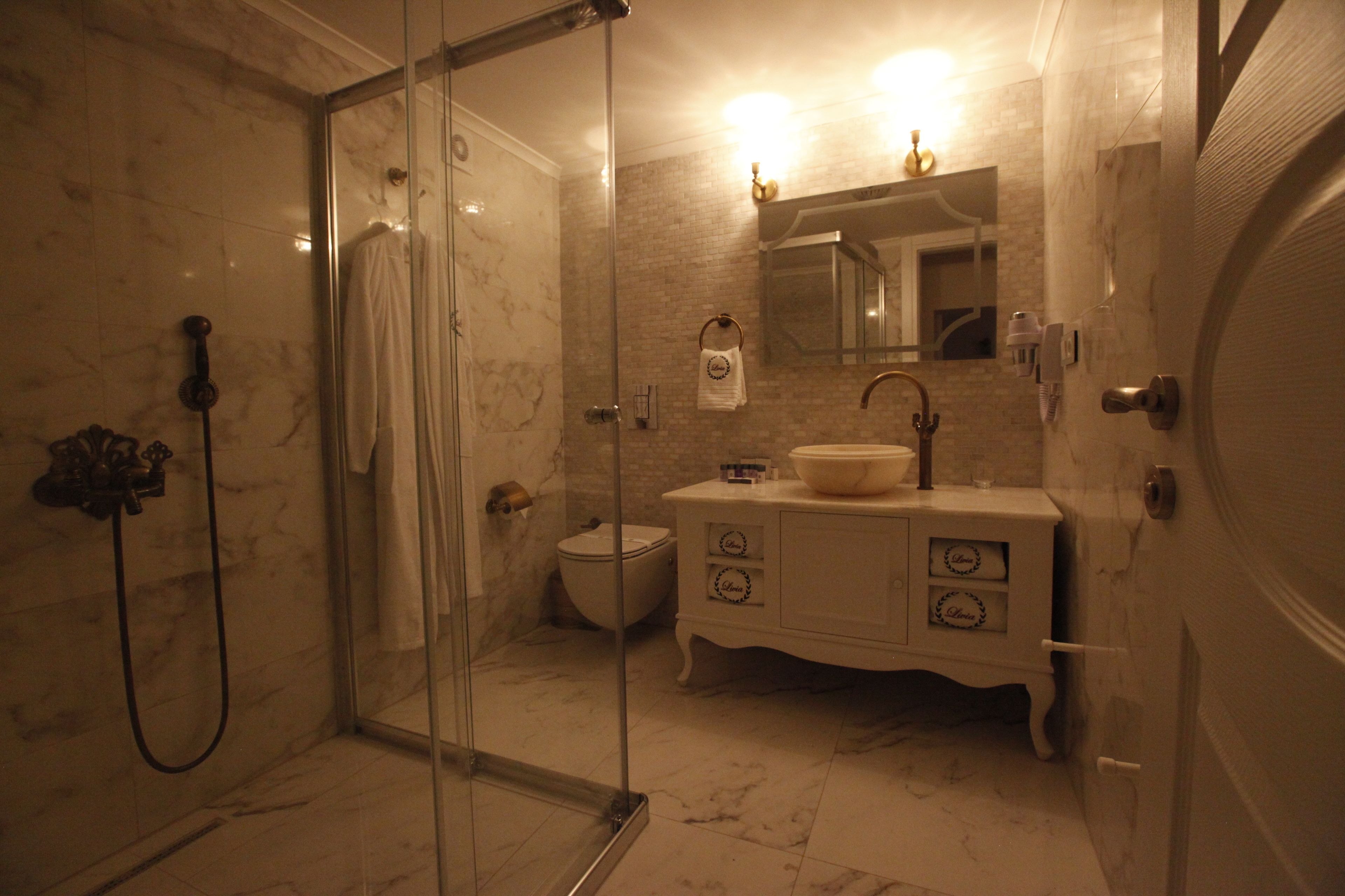 Ein Badezimmer mit einer Duschkabine, einer Toilette, einem Waschbecken mit Spiegel darüber und einem Waschtisch mit Schubladen.