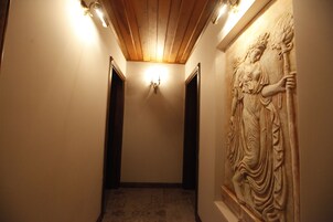 Un pasillo con techo de madera, una escultura en la pared y una lámpara.