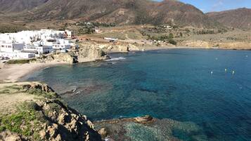 Un pueblo costero con edificios blancos, una playa y montañas al fondo.