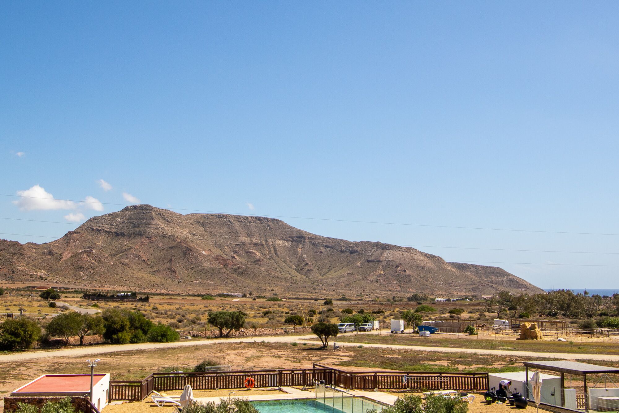 A pool area with a wooden deck, a lifebuoy, and a mountain in the background.