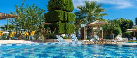 A swimming pool with lounge chairs and a tropical garden.