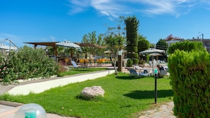 A sunny outdoor area with a pool, lounge chairs, and umbrellas. - Stamos Hotel (Rhodes)