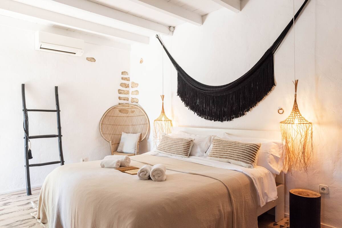 A bed with a hammock, a ladder, and a wall with stones.