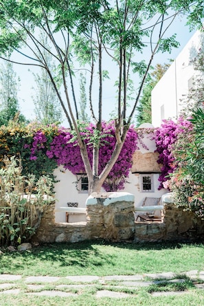A stone wall with a window and a tree with purple flowers. - Can Sastre Boutique Hotel (Sant Antoni de Portmany)