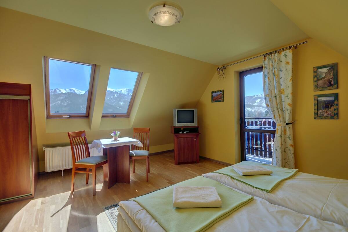 Un dormitorio con dos camas, televisión, mesa de comedor y sillas.
