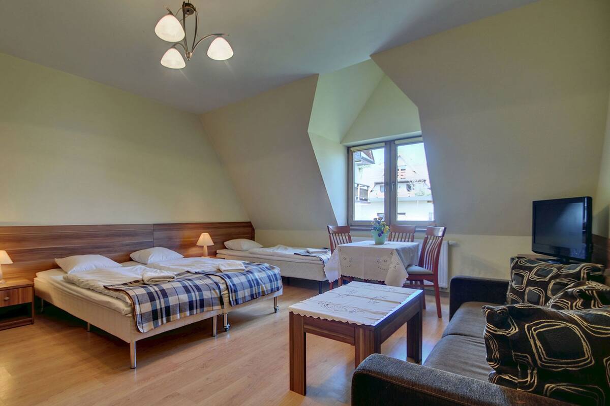 Una habitación de hotel con cama, sofá, televisión y mesa de comedor.