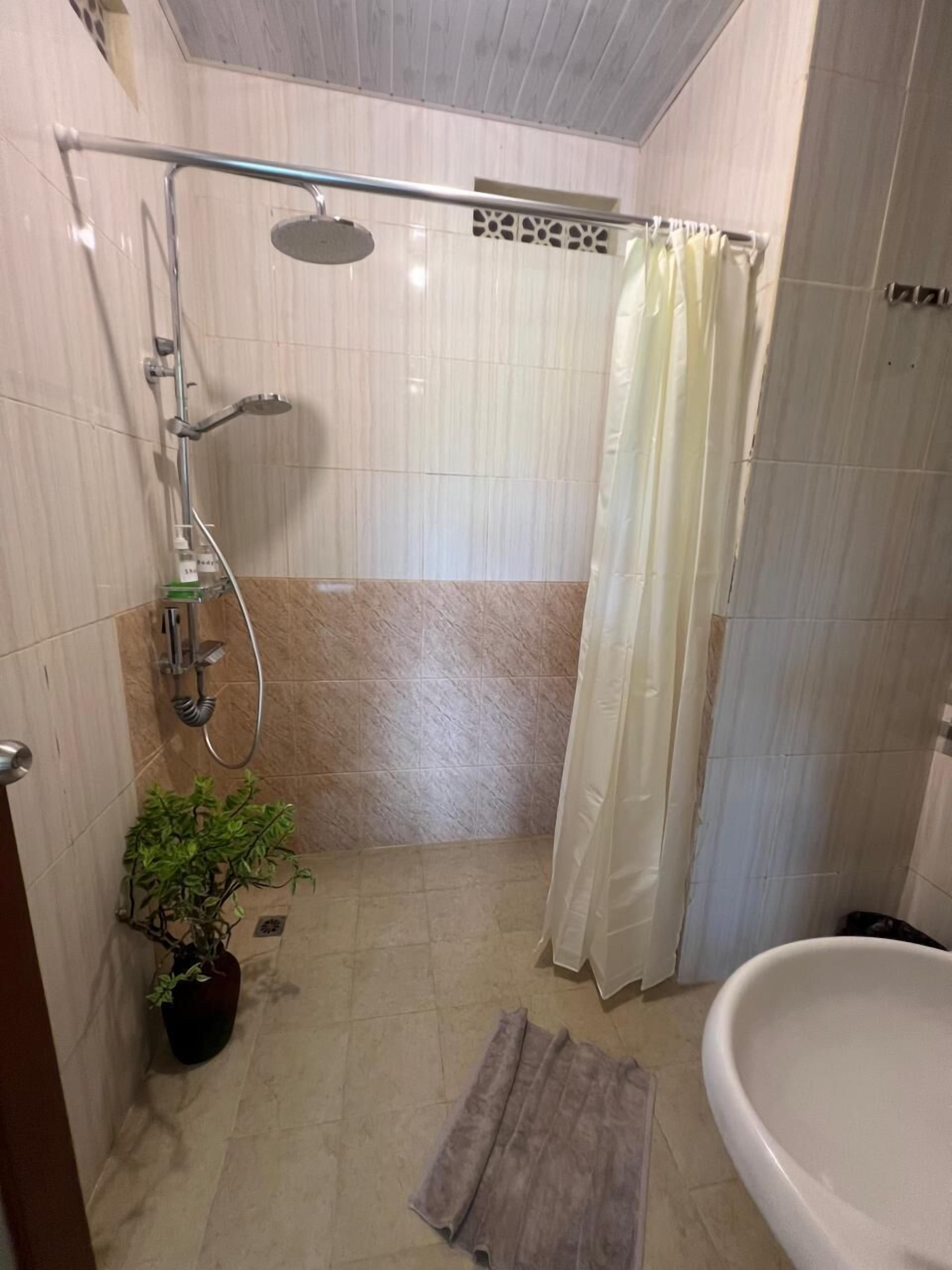 A small, tiled bathroom with a shower, a toilet, and a sink.