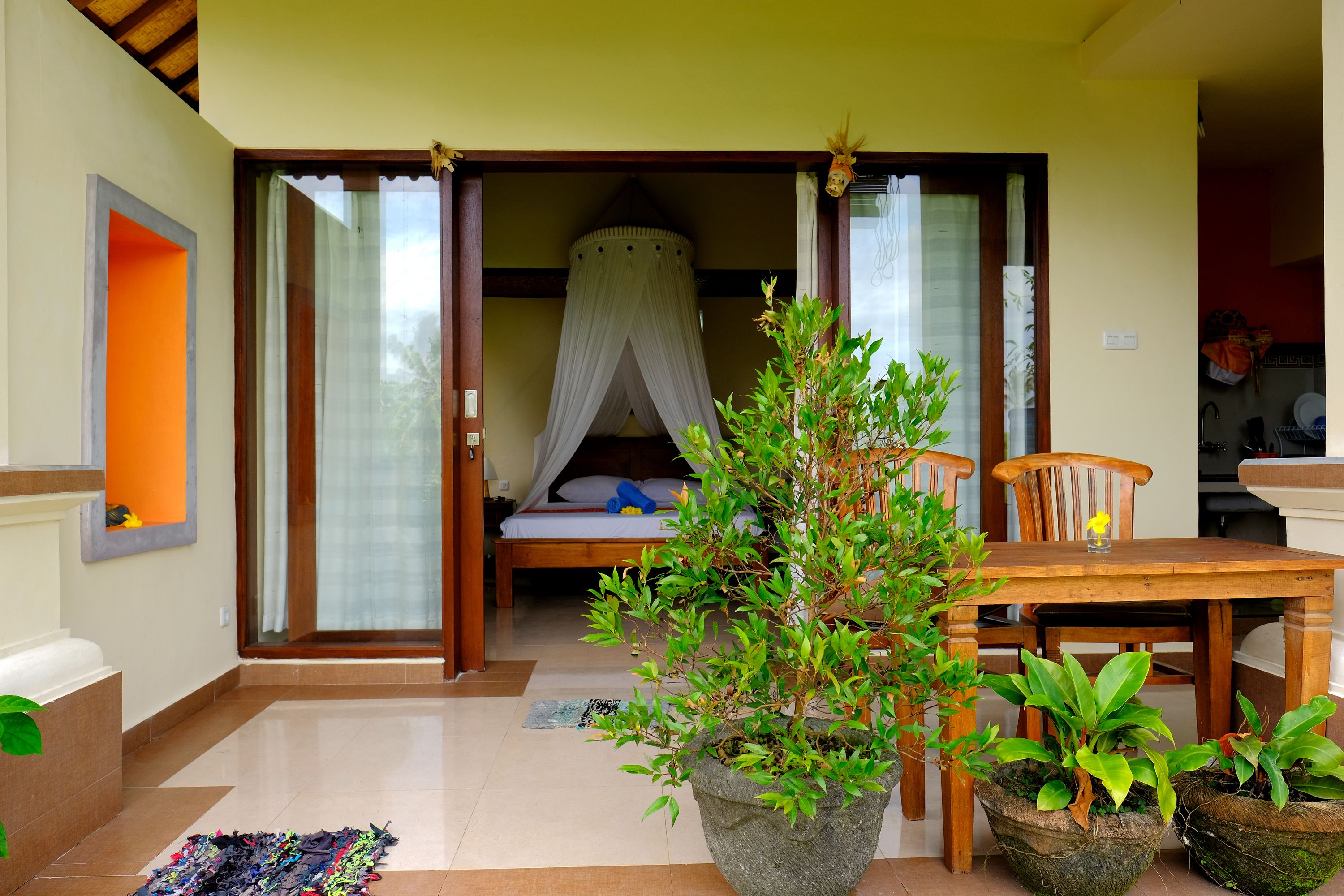 Quarto com cama, mesa de jantar e plantas em vasos.