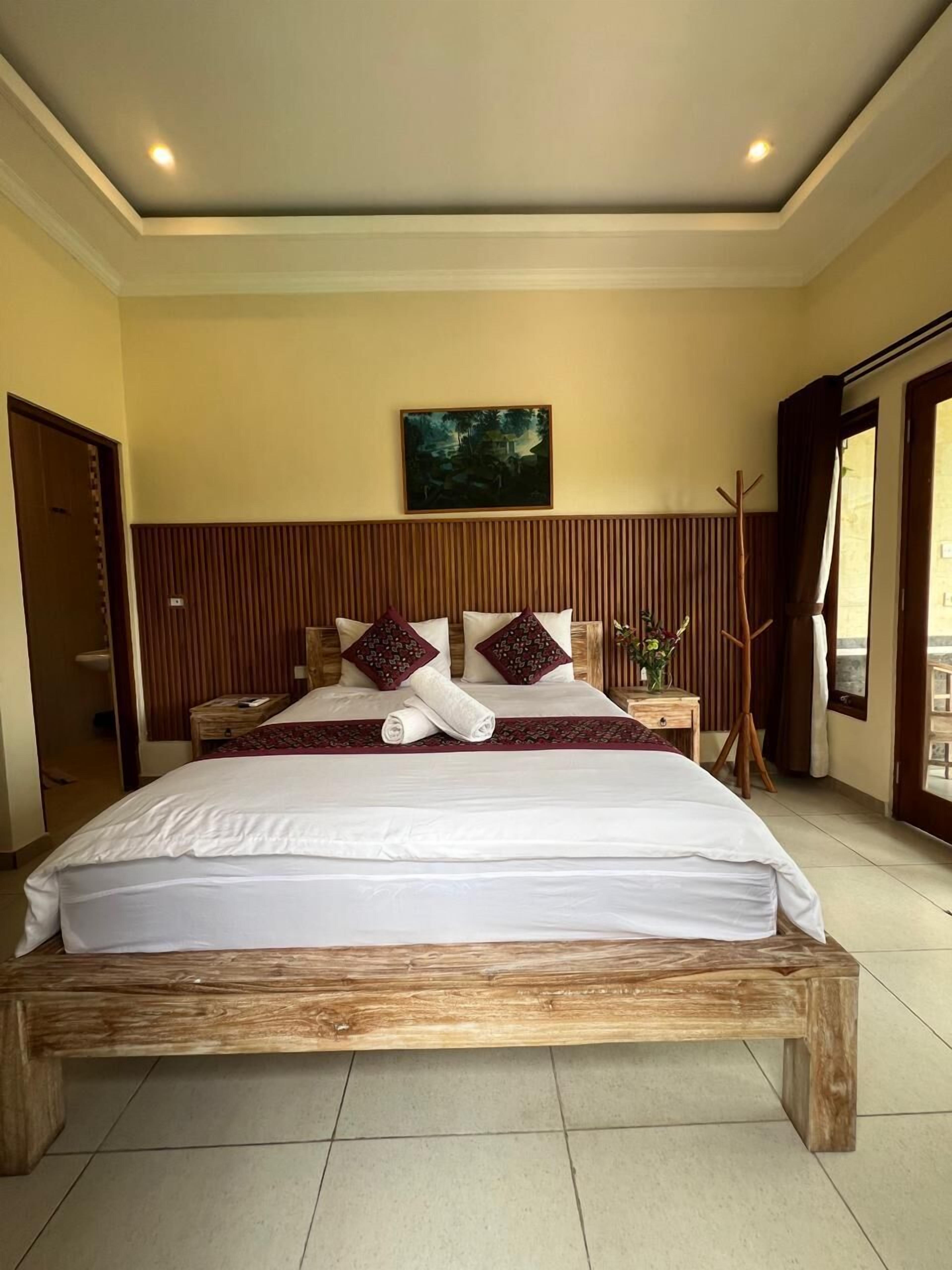 A large bed with a wooden frame, white bedding, and two decorative pillows.