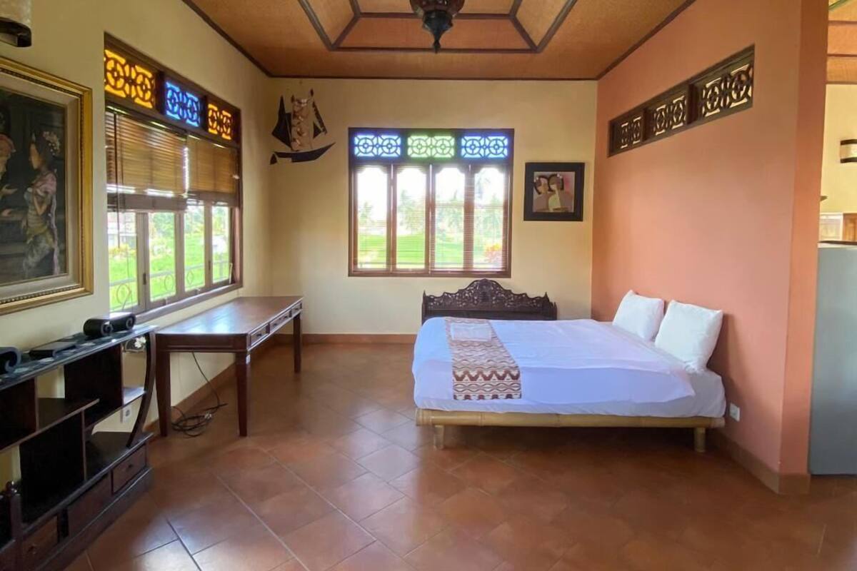 Een slaapkamer met een bed, een bureau en een raam met decoratieve luiken.
