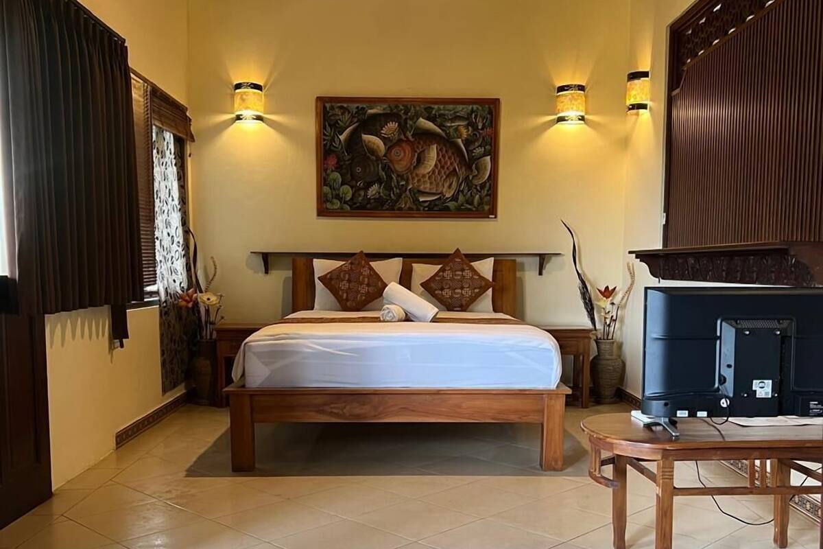 Een slaapkamer met een bed, een televisie en een plafondlamp.