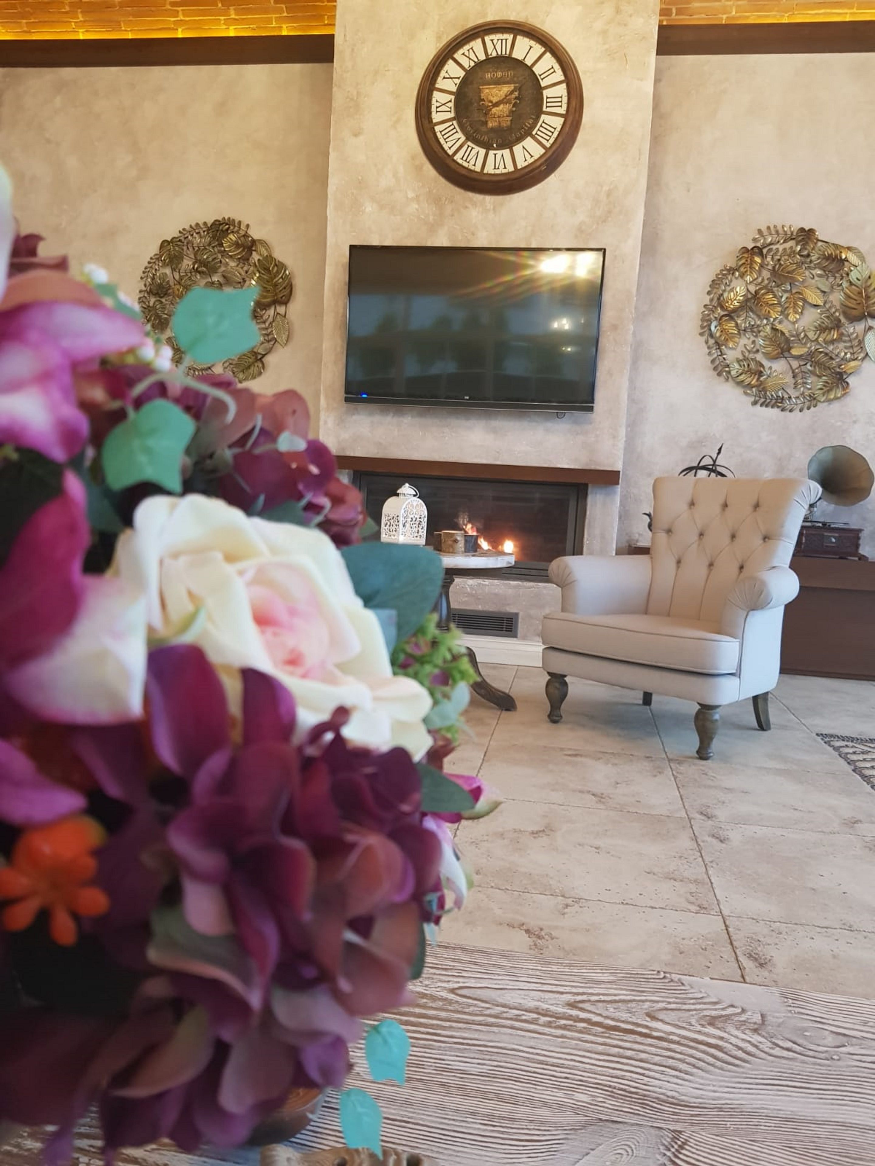A living room with a fireplace, a television mounted on the wall, and a decorative clock.
