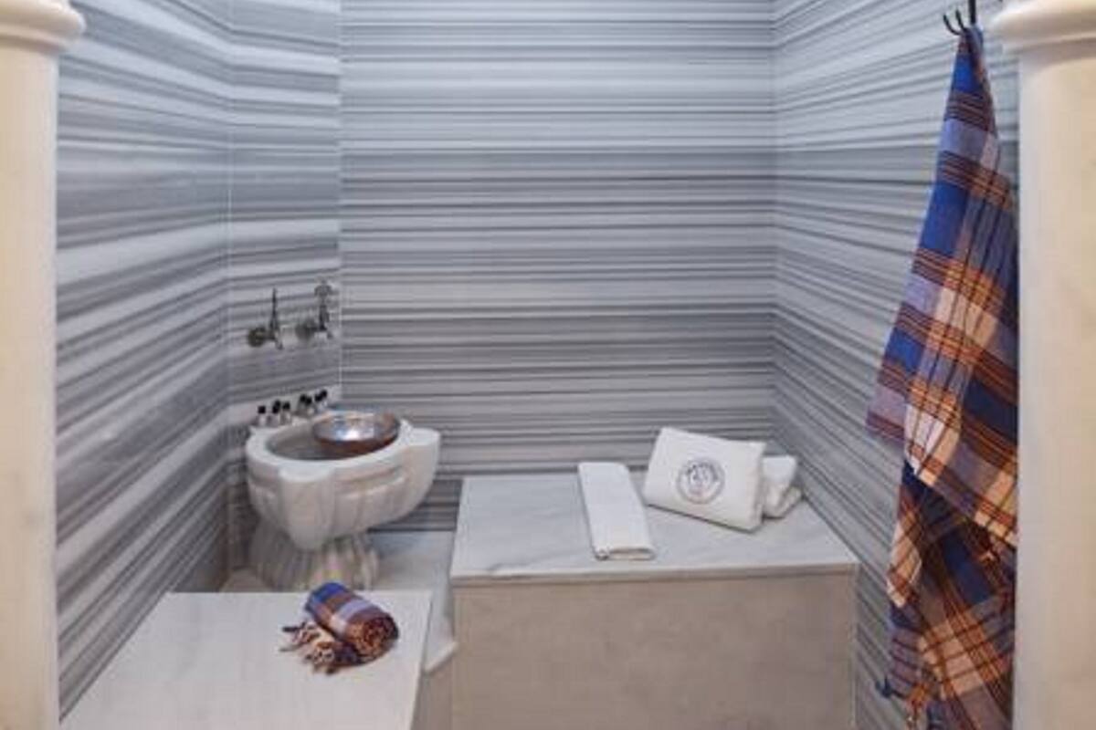 Baño con tocador de mármol, lavabo y zona de ducha.