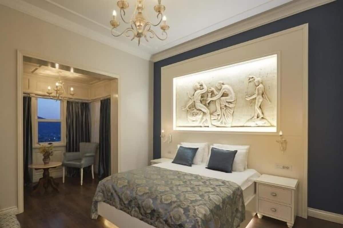 Un dormitorio con una cama, una mesita de noche, una silla, una mesa y una escultura en la pared.