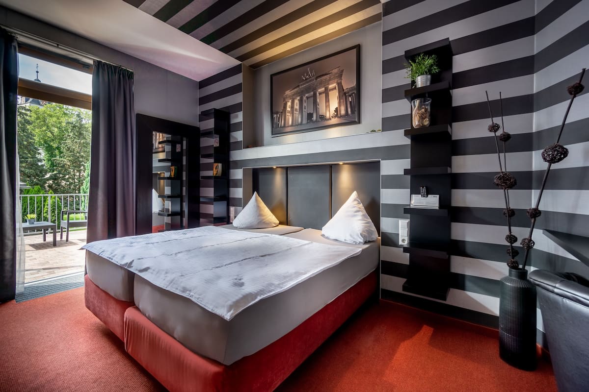 Een moderne hotelkamer met een groot bed, uitzicht op de omgeving en een gestreept wandontwerp.