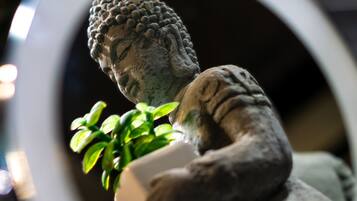 Eine Statue einer sitzenden Figur, die eine Pflanze hält, betrachtet durch einen runden Spiegel.