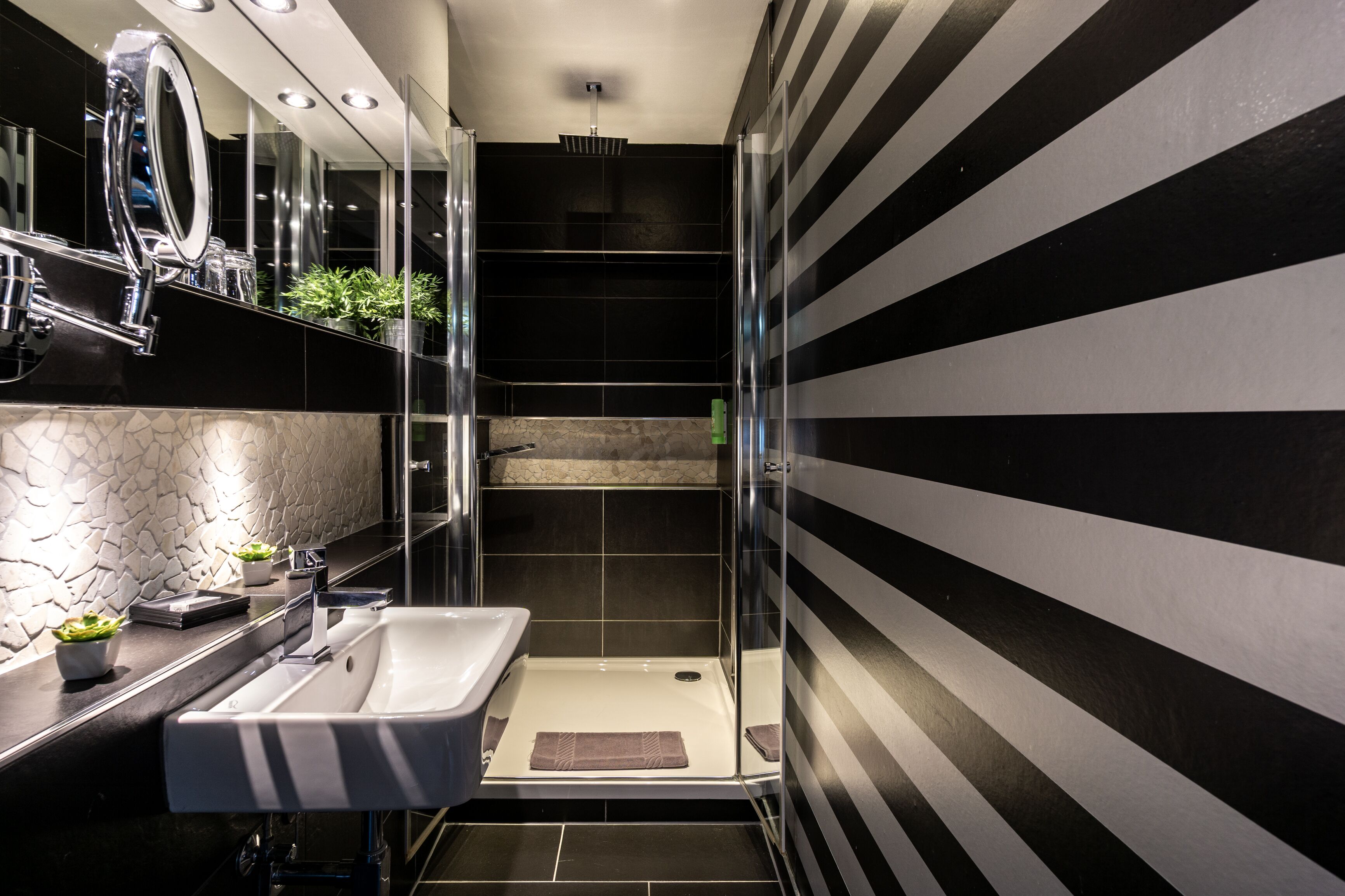 A modern bathroom with a large mirror, a sink, and a shower area.