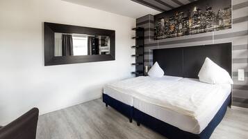 Un dormitorio moderno con una cama grande, una obra de arte urbana en la pared, un espejo y suelo de madera.