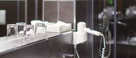 A modern bathroom with a large mirror, a white sink, and a handheld showerhead.