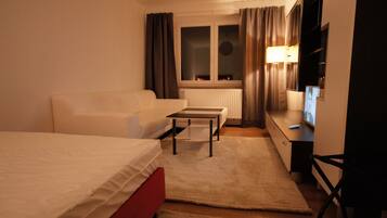 Une chambre d’hôtel avec un lit, un canapé, une petite table, une télévision et un radiateur.