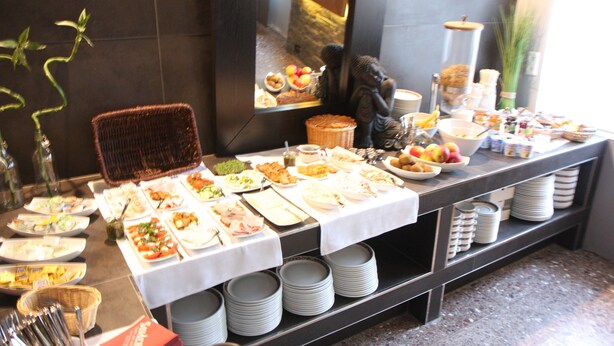 A buffet table with various food items and a wicker chair. - SL'otel - Budget (Bernburg)