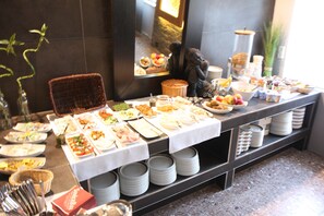 Una mesa de buffet con diversos alimentos y una silla de mimbre.