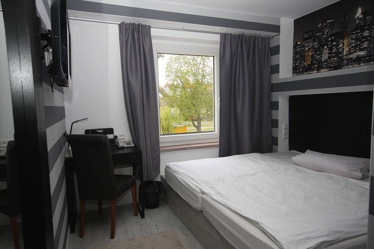 A bedroom with a bed, a desk, and a chair.