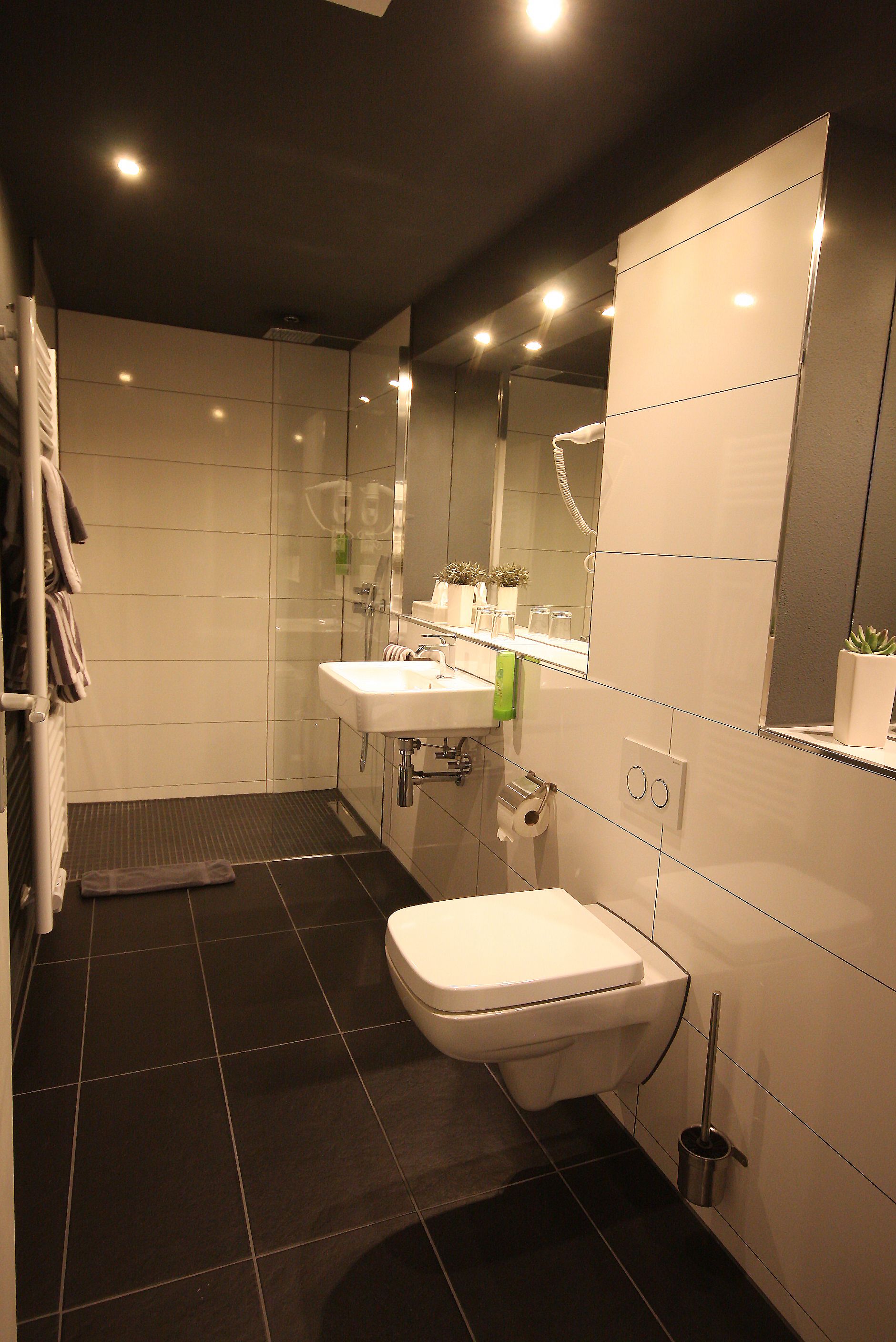 A modern bathroom with a toilet, sink, and shower.