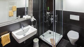 A modern bathroom with a glass-enclosed shower, a white sink, and a toilet.