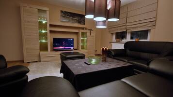 Una sala de estar moderna con televisor de pantalla plana, sofás de cuero, una mesa de centro e iluminación colgante.