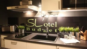 A modern kitchen with a black countertop, stainless steel sink, and a sign that reads "SL Hotel Budget." - SL'otel - Budget (Bernburg)