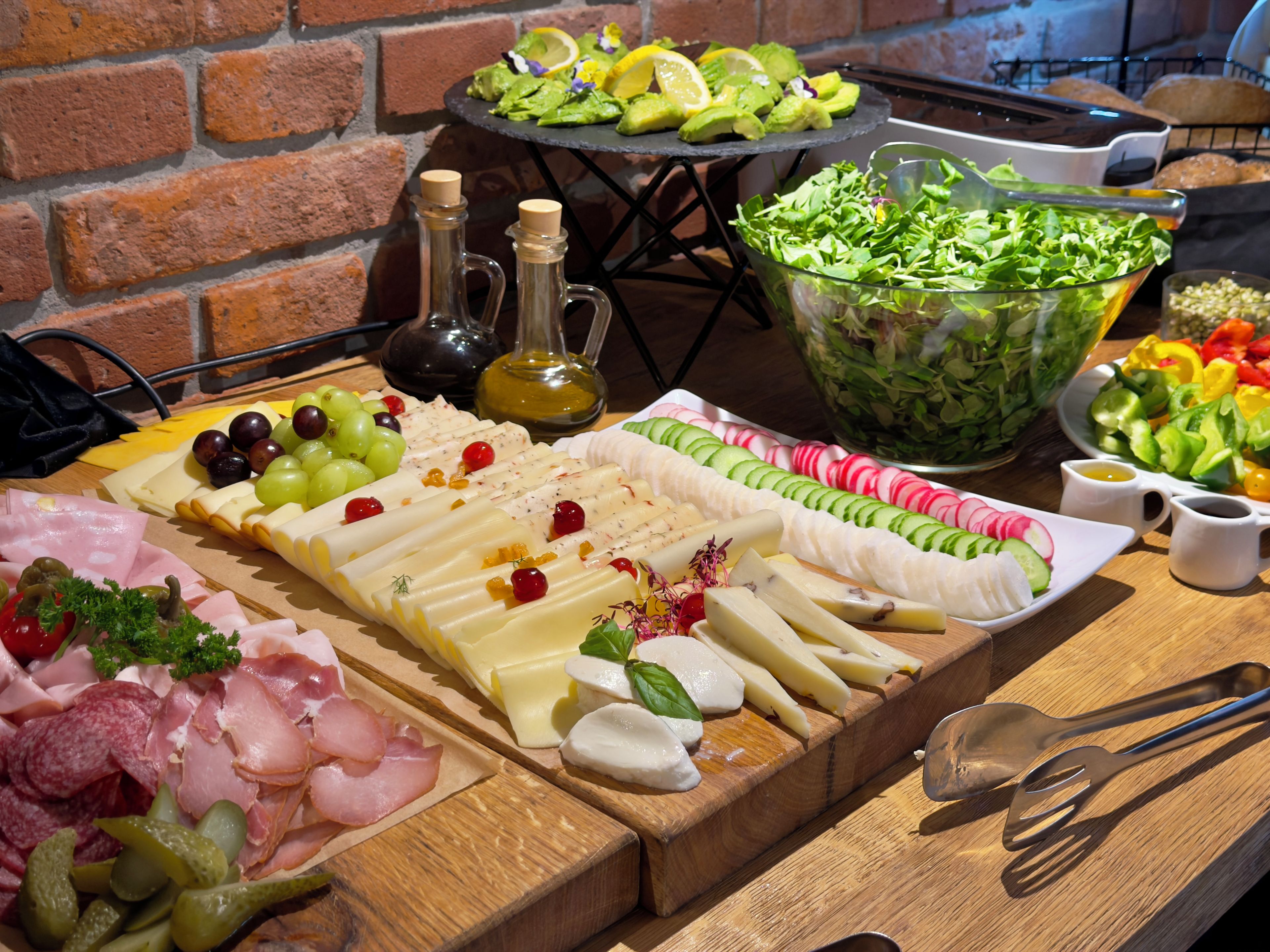 Una variedad de alimentos, incluyendo quesos, carnes y ensaladas, sobre una tabla de madera.