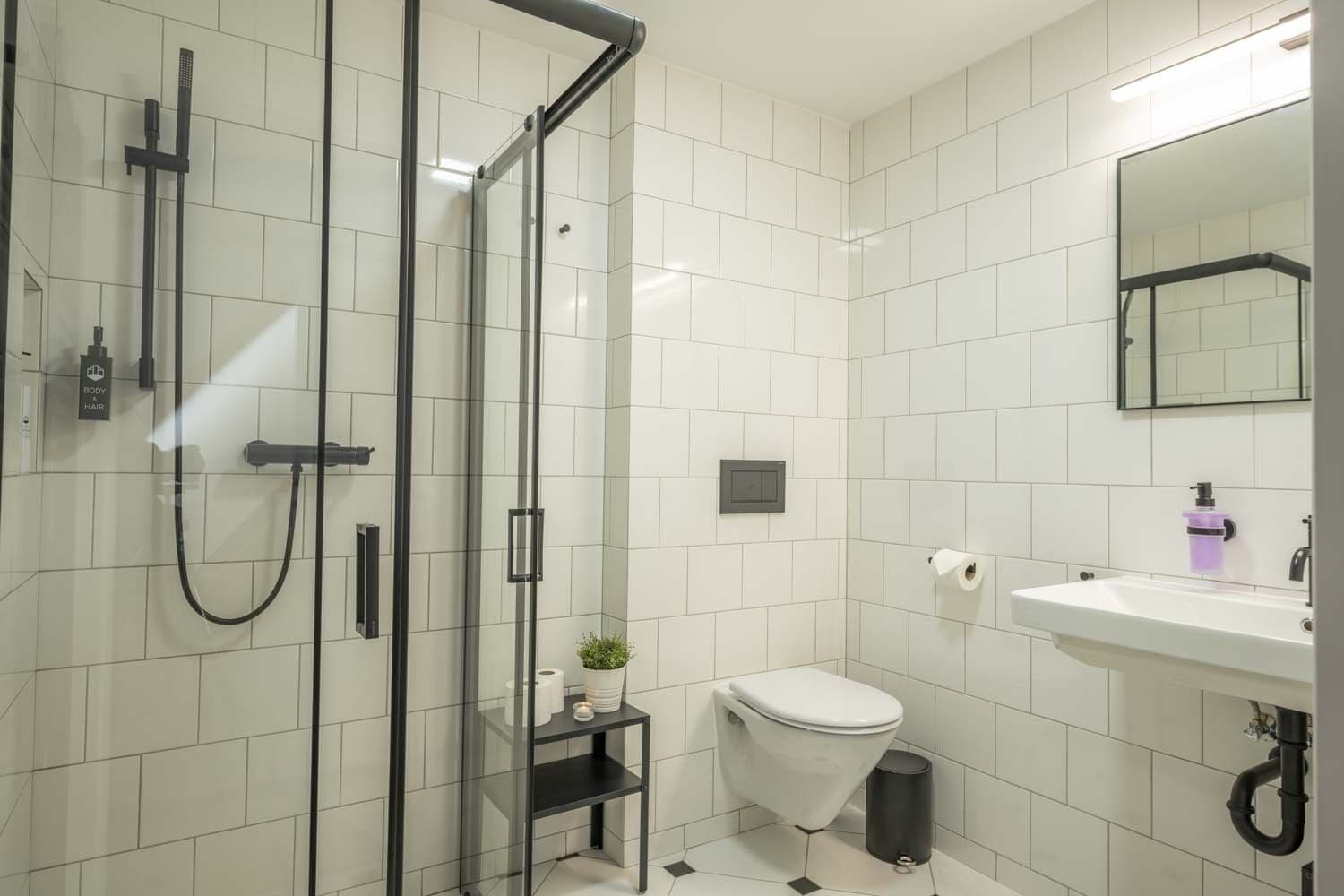 Ein modernes Badezimmer mit Duschkabine aus Glas, Toilette, Waschbecken und Spiegel.