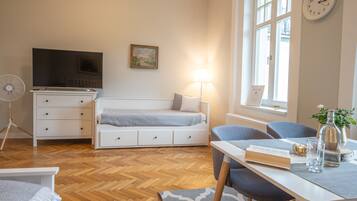 A modern room with a bed, a desk with a lamp, a TV, and a clock on the wall.