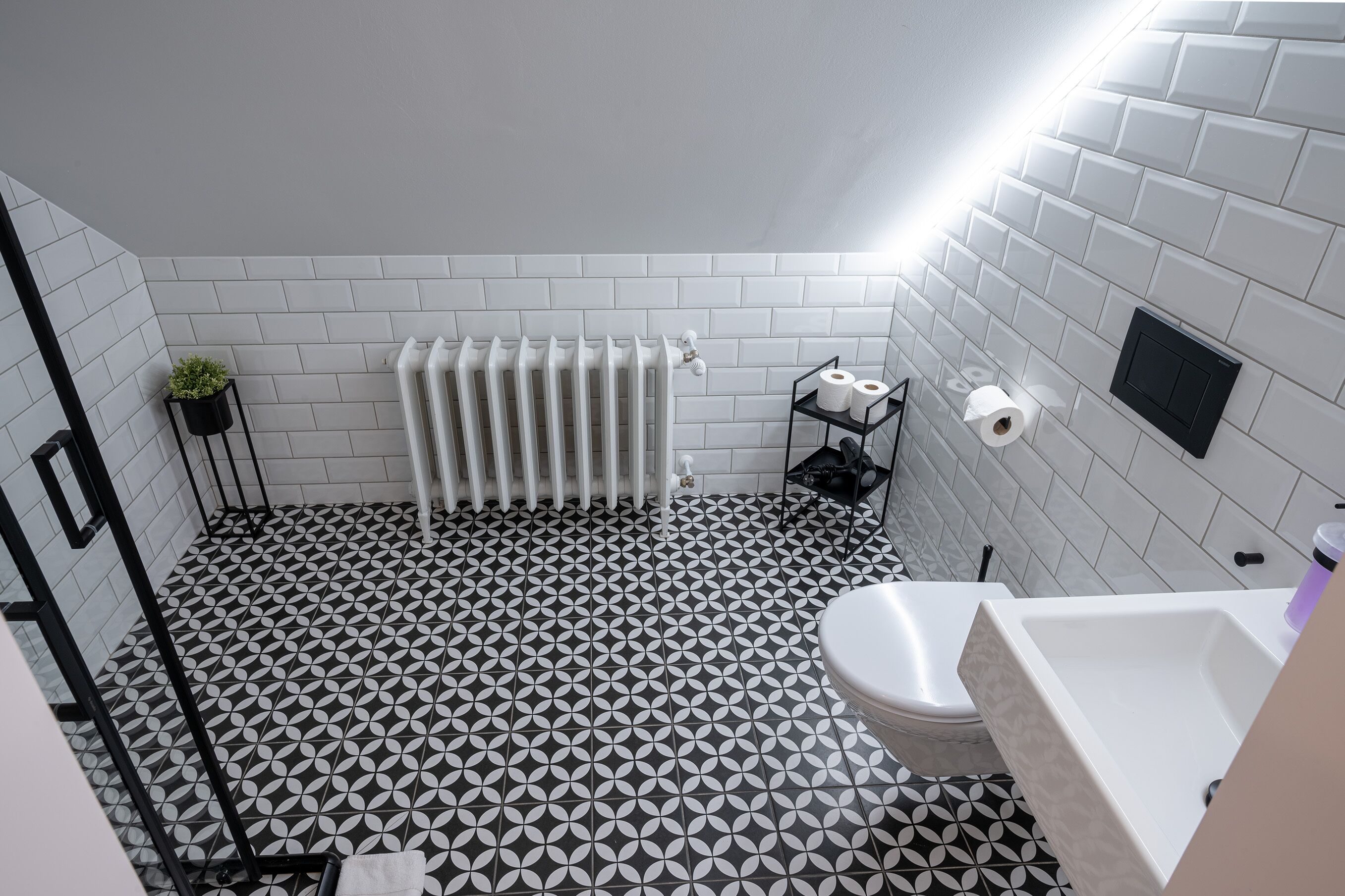 Une salle de bain avec un carrelage noir et blanc, un radiateur blanc, des toilettes et un lavabo avec un miroir.